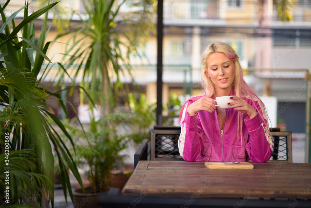Happy young beautiful blonde woman relaxing at the coffee shop