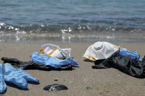 Protective virus mask and plastic gloves garbage trash on sandy sea shore,coronavirus covid pollution disease 