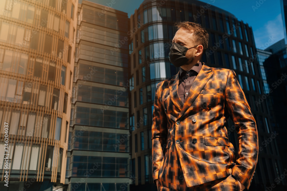 Portrait of a young man in medical black mask looks forward against the background of business center. average plan