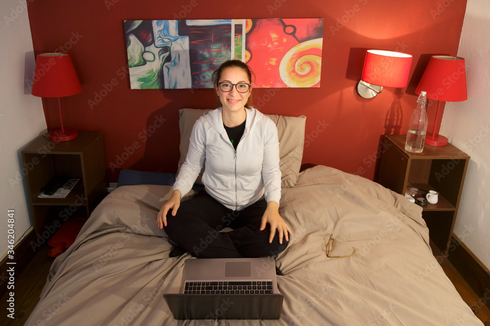 Fototapeta premium ragazza seduta nel suo letto di casa sorride felice