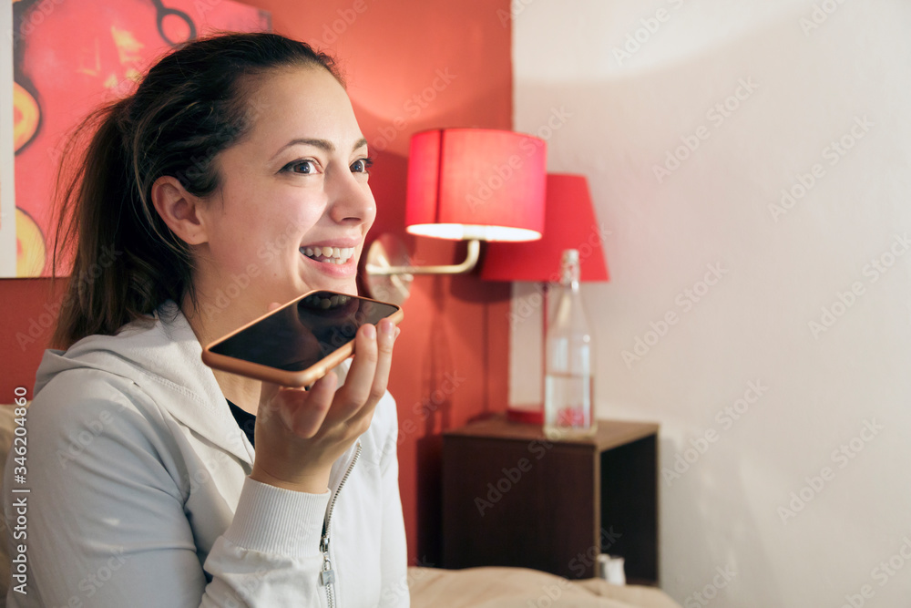ragazza manda un messaggio vocale con lo smartphone dalla sua stanza ragazza manda un messaggio vocale con lo smartphone dalla sua stanza