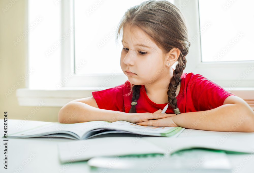 the child is studying at home. Distance learning. A girl sits by the window and does homework.
the child is studying at home. Distance learning. A girl sits by the window and does homework.