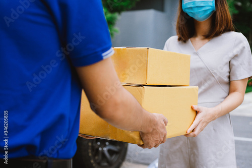 young women wear mask accepting a delivery of boxes from delivery service courier