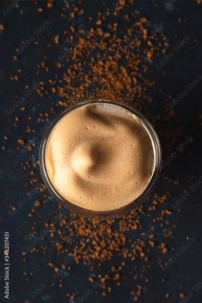 Homemade dalgona coffee made of instant coffee, sugar and milk on a dark background with ice. Top view Homemade dalgona coffee made of instant coffee, sugar and milk on a dark background with ice. Top view