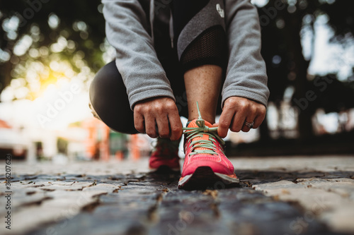Closeup of woman tying shoelace at sunrise