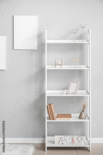 Rack with stylish decor near grey wall in room