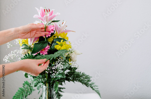 A person prepares a beautiful bouquet of yellow, pink and green flowers.