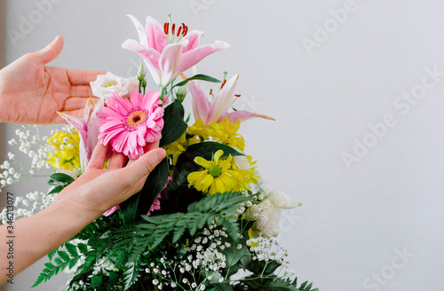 A person prepares a beautiful bouquet of yellow  pink and green flowers.
