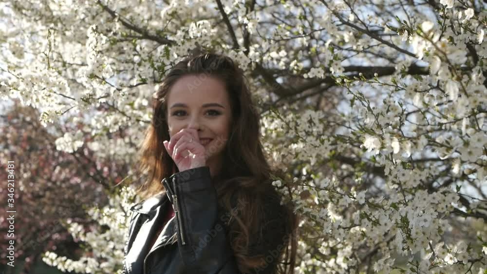 Young pretty smiling caucasian woman standing near blooming spring tree. Young pretty smiling caucasian woman standing near blooming spring tree.