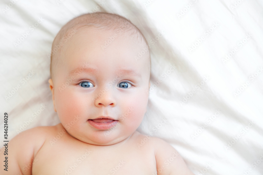 Cute happy baby in white sunny bedroom, lying in bed Cute happy baby in white sunny bedroom, lying in bed
