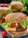 Photo homemade burgers with beef, onions, tomatoes, lettuce, cheese and spices. Fresh burgers on a wooden Board with cherry tomatoes.