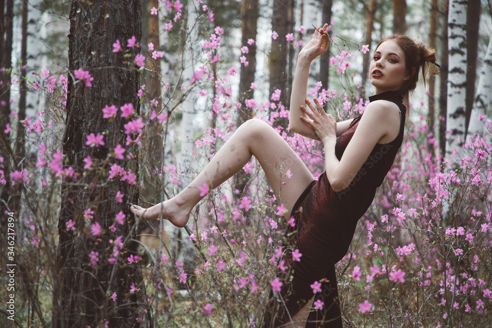 A girl dressed in Japanese style in a flowering forest among pink flowers A girl dressed in Japanese style in a flowering forest among pink flowers