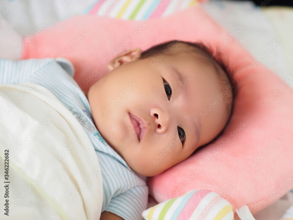 A cute Asian 2-month-old baby girl is lying down on a soft and comfortable mattress, with pillow and blanket. Close up shot. A cute Asian 2-month-old baby girl is lying down on a soft and comfortable mattress, with pillow and blanket. Close up shot.