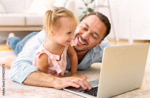 Father and daughter watching cartoons at home © Prostock-studio