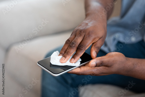 Unrecognizable African American Man Cleaning His Smartphone With Antibacterial Tissues