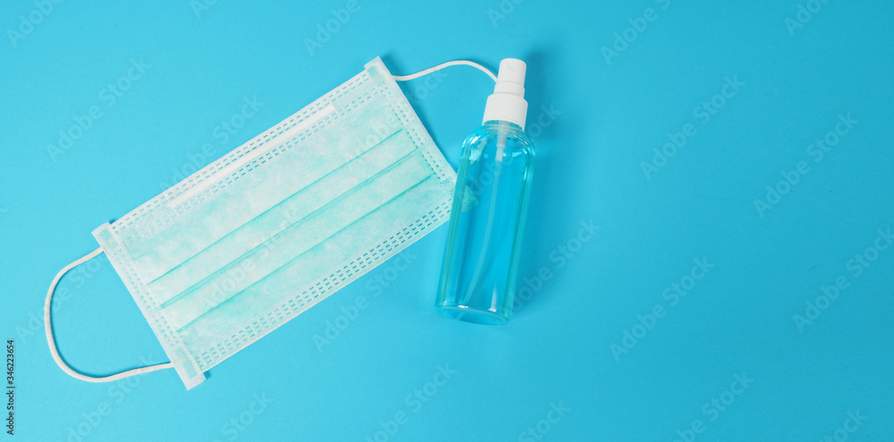 Alcohol spray and face mask to prevent virus on blue background. Alcohol spray and face mask to prevent virus on blue background.