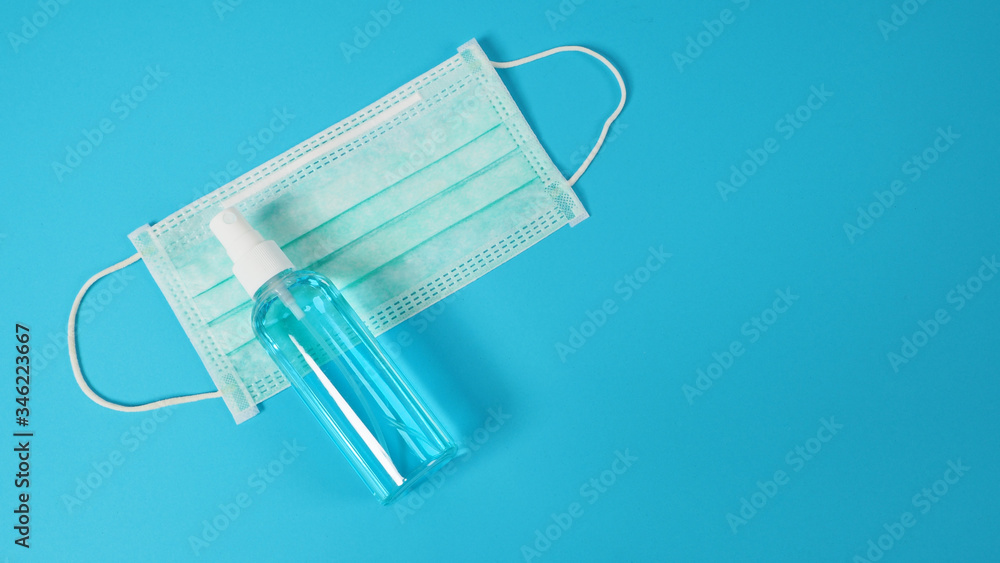 Alcohol spray and face mask to prevent virus on blue background. Alcohol spray and face mask to prevent virus on blue background.