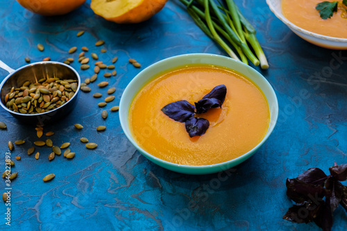 pumpkin soup with purple Basil on a blue background. Top View