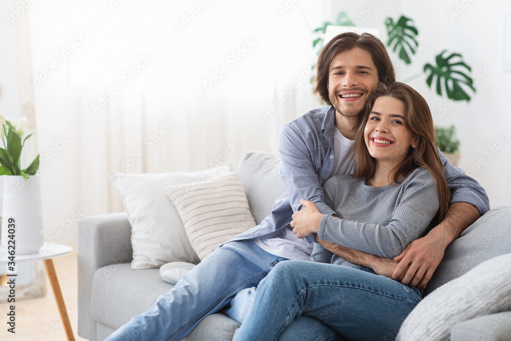 Young man and woman hugging and looking at camera
