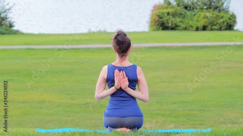 Yoga practicing in nature, view from behind, muscles stretching