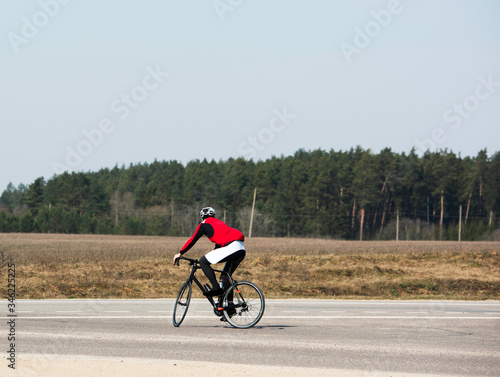 Joyful male bicyclist cycling in empty road during the coronavirus (COVID-19) pandemic lockdown, crossing the road, enjoying the view, copy space. Athlete cycling on the road. no cars.