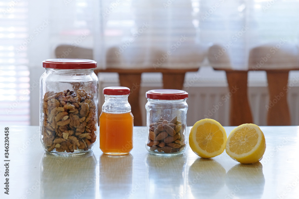 jars of walnuts, honey, almond, and two slices of lemon jars of walnuts, honey, almond, and two slices of lemon