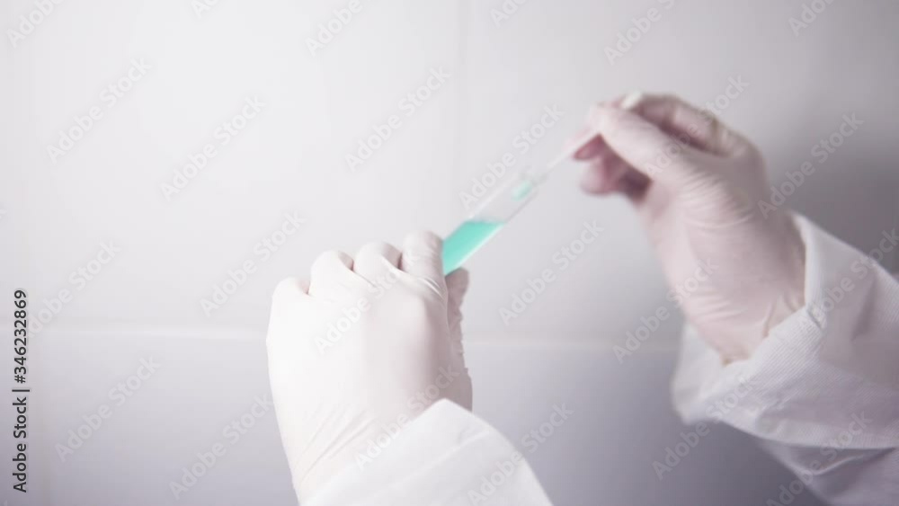 Nurse doctor or scientist wearing protective gear suit and gloves dipping a cotton bud inside a test tube full of coronavirus vaccine sample against white background Nurse doctor or scientist wearing protective gear suit and gloves dipping a cotton bud inside a test tube full of coronavirus vaccine sample against white background