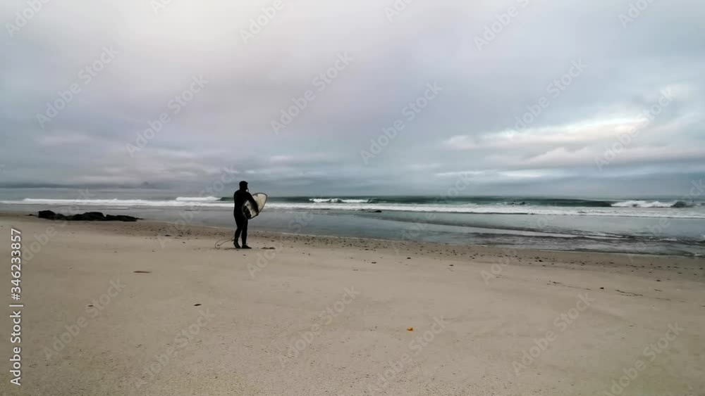 Surfer at dawn picks up his board and heads to the sea