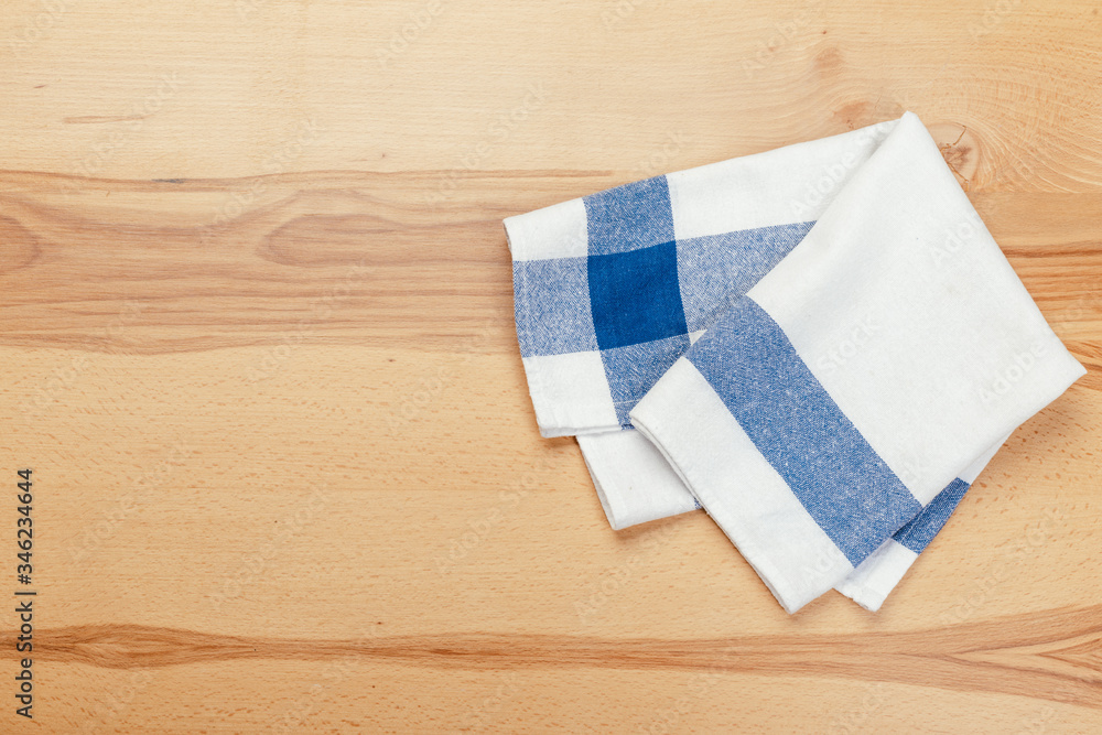 Top view on a wooden table with a linen kitchen towel or textile napkin.