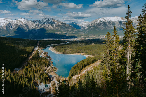 Fototapeta Naklejka Na Ścianę i Meble -  Top/Aerial view of Rundle Forebay Reservoir surrounded by forests and Canadian Rockies on background with Canmore town. Grassi Lakes, Alberta, Canada