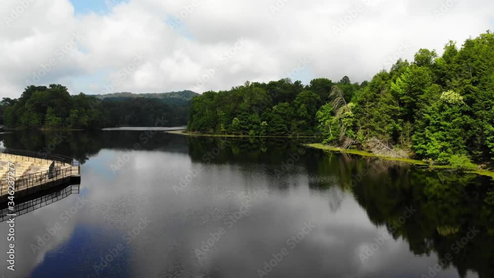 Starting just above the water, rising above the calm water that has a reflection of the clouds, turning to the left and flying past the dam. Continuing straight towards where the water splits. Starting just above the water, rising above the calm water that has a reflection of the clouds, turning to the left and flying past the dam. Continuing straight towards where the water splits.