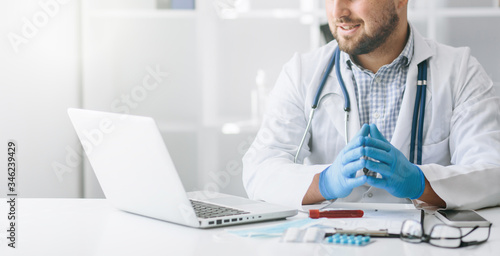 Young handsome doctor in gloves with patient online consultate photo