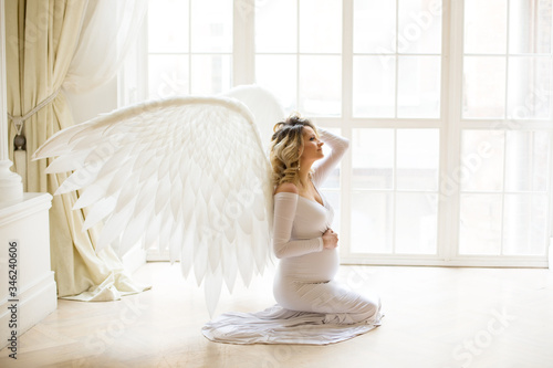 Pregnant woman at white dress with wing