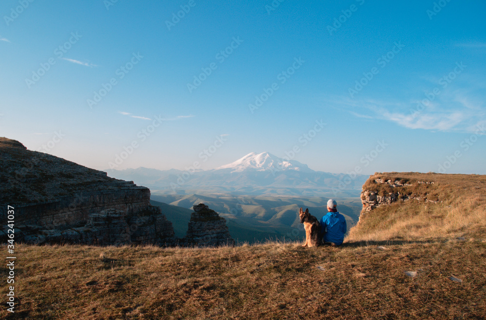 Girl and dog on the background of Elbrus. A girl and a German shepherd travel through the mountains together.