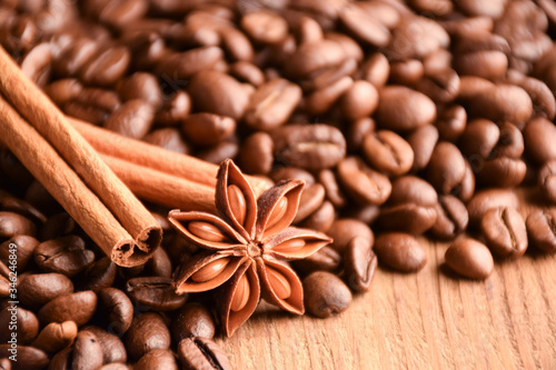  Scattered grains of coffee, anise and cinnamon on a wooden background