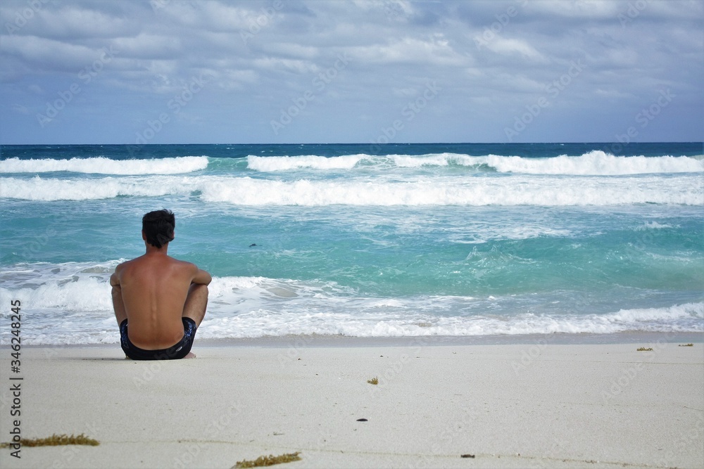 A man sits on a wild ocean beach A man sits on a wild ocean beach