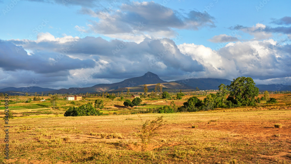 Typical Madagascar landscape - green and yellow rice terrace fields on small hills with clay houses in distance - Andringitra region near Sendrisoa