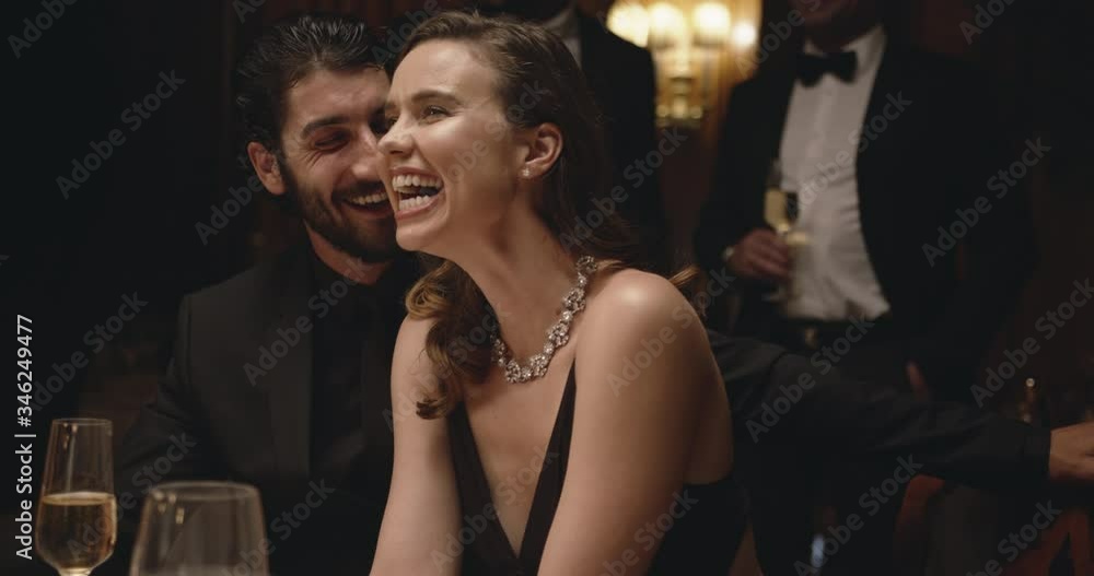 Handsome young man talking with a pretty woman sitting at dinner party. Cheerful couple at gala night.