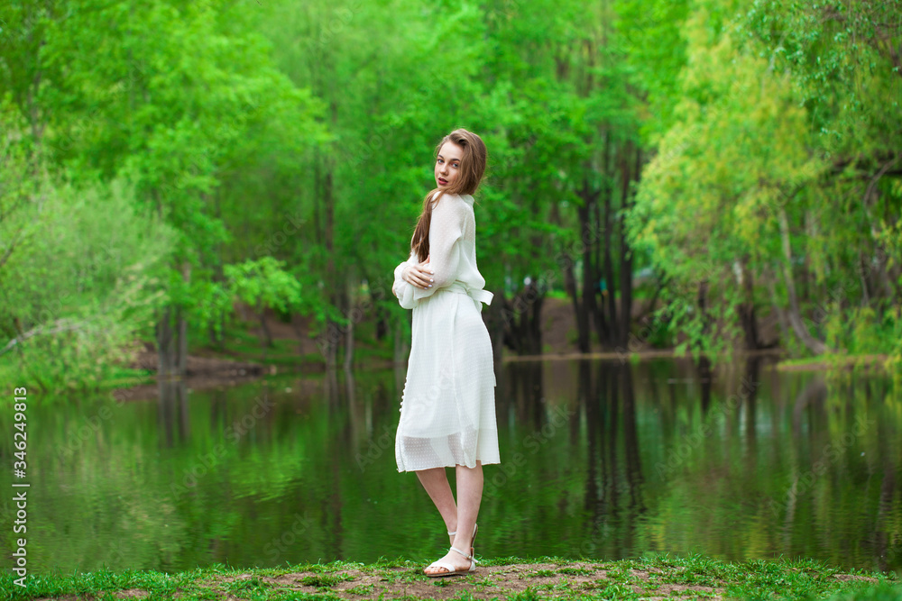 Portrait of a young beautiful woman in white dress posing by the lake Portrait of a young beautiful woman in white dress posing by the lake