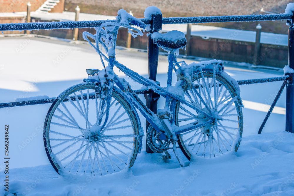 Bicycle in the frost standing at the railing in the winter morning