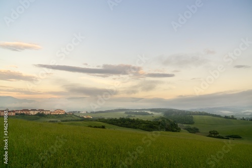 Sunrise and sunset, beautiful clouds over the meadow, hills and buildings in the town. Slovakia © Valeria