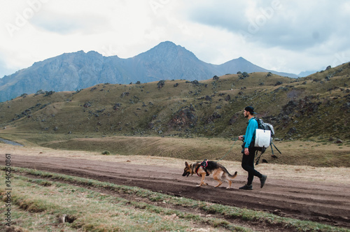 A man and a dog in the mountains. A guy with a German shepherd traveling in the mountains.