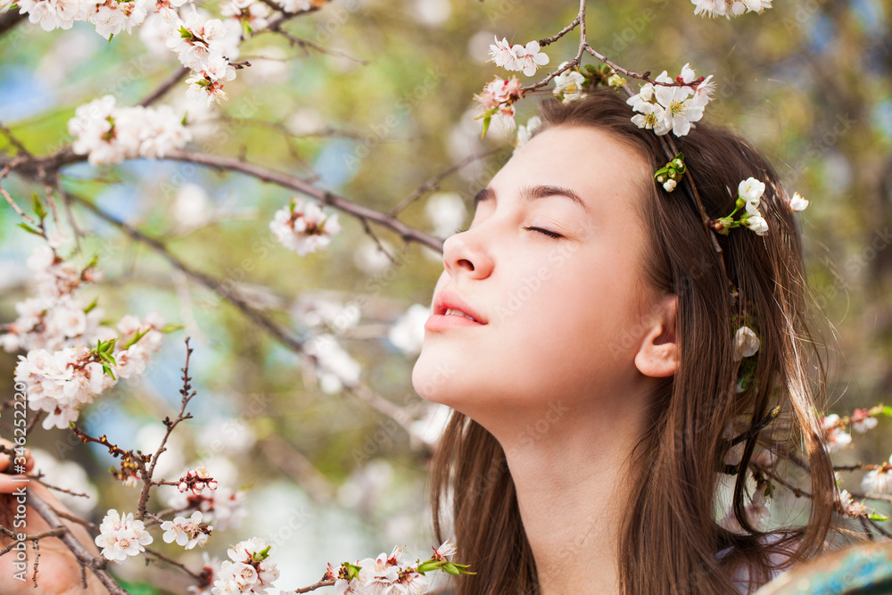 Pretty teen girl are posing in garden near blossom cherry tree with white flowers Pretty teen girl are posing in garden near blossom cherry tree with white flowers