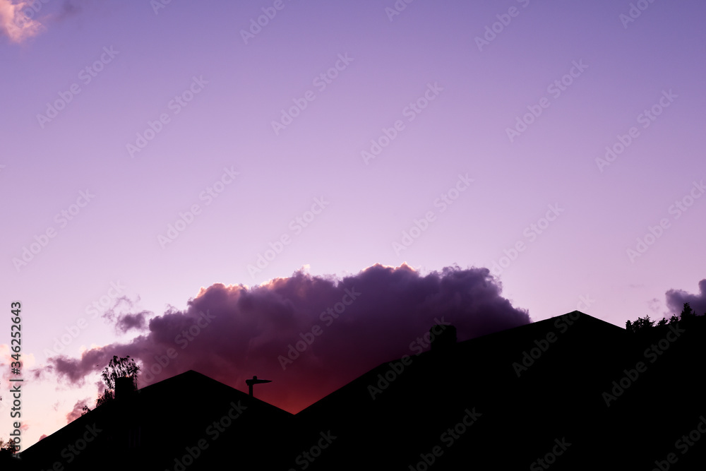 Houses on a suburban street silhouetted in evening sky