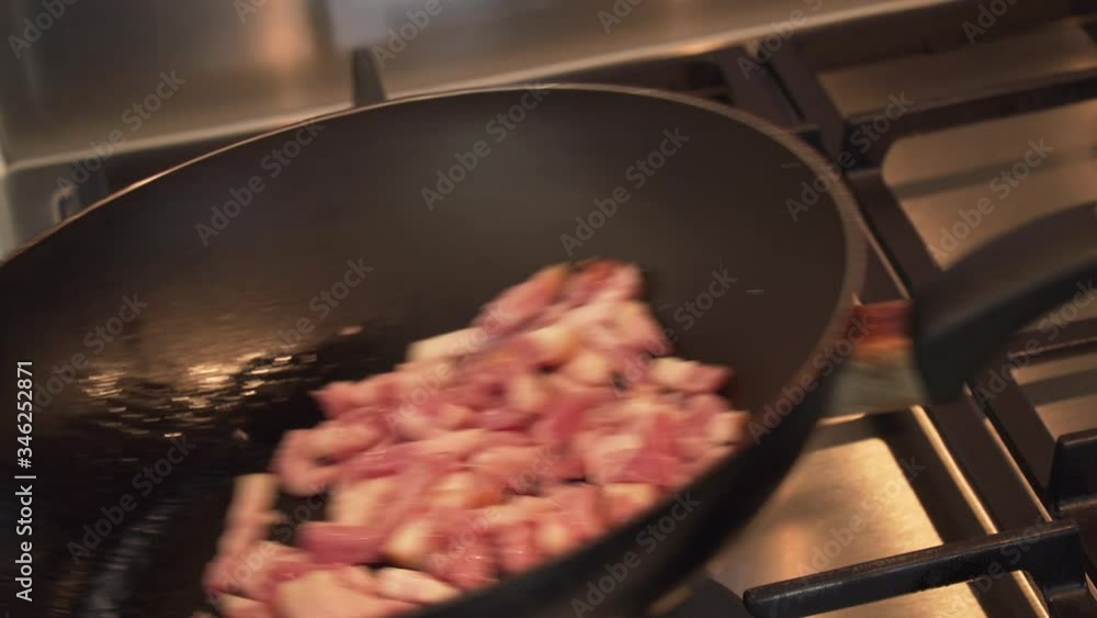 Tossing bacon strips around in a frying pan, chef cooking breakfast ingredients Tossing bacon strips around in a frying pan, chef cooking breakfast ingredients