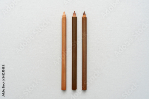 Three neutral color pencils on a white canvas