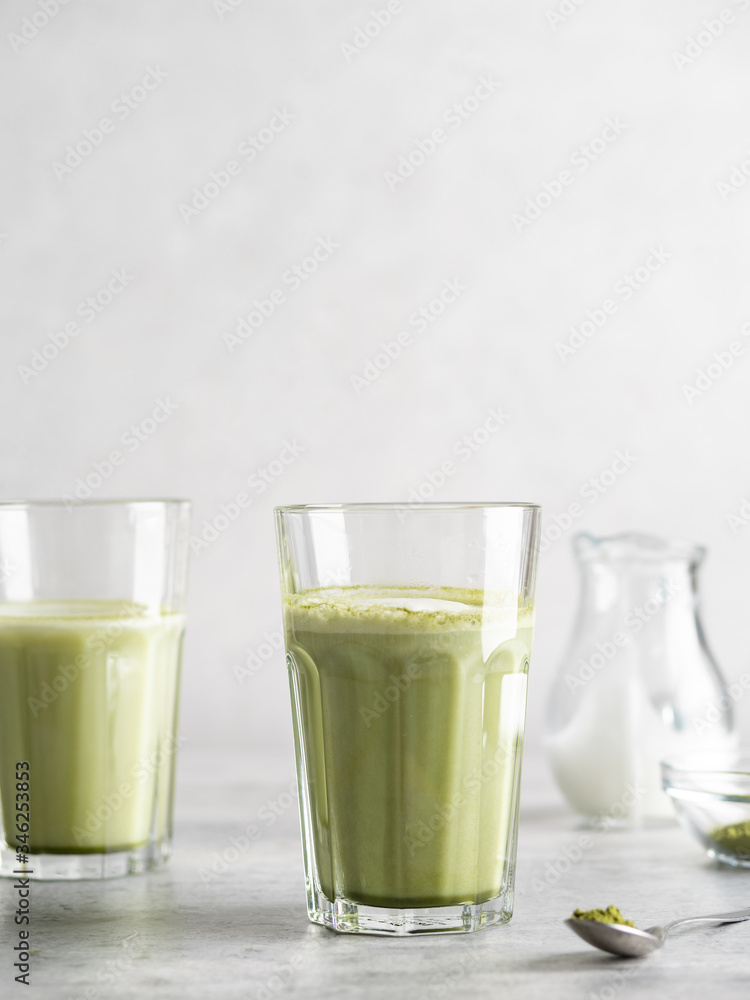 Matcha latte glass. Green tea antioxidant beverage with plant based milk. Creamy delicious non dairy vegetarian drink. Healthy organic coffee alternative. Copy space. Light grey concrete background. Matcha latte glass. Green tea antioxidant beverage with plant based milk. Creamy delicious non dairy vegetarian drink. Healthy organic coffee alternative. Copy space. Light grey concrete background.