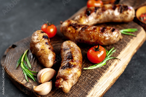 grilled sausage with spices and rosemary on
cutting board on stone background