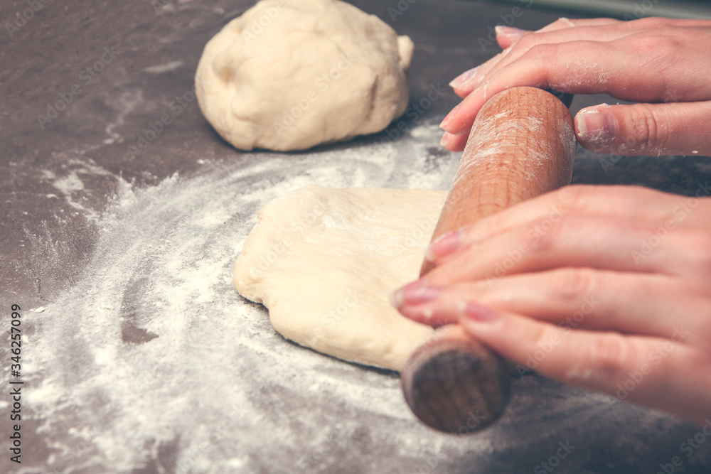 cook woman hands roll out the dough on the table cook woman hands roll out the dough on the table