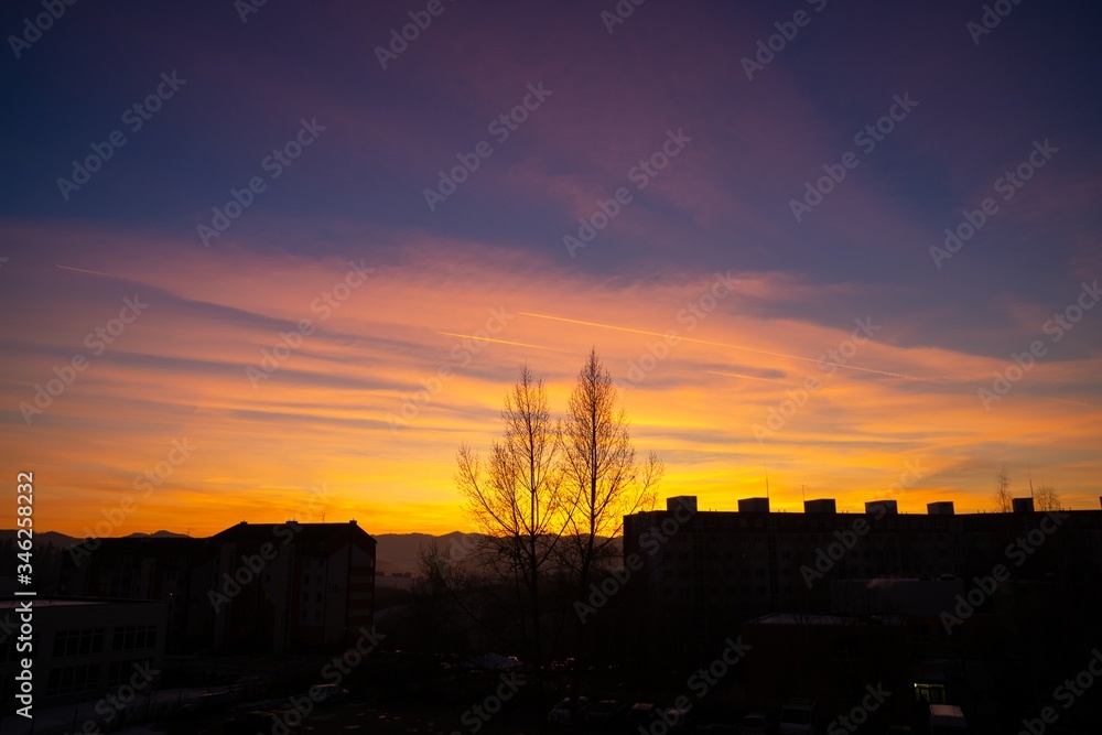 Sunrise and sunset, beautiful clouds over the meadow, hills and buildings in the town. Slovakia